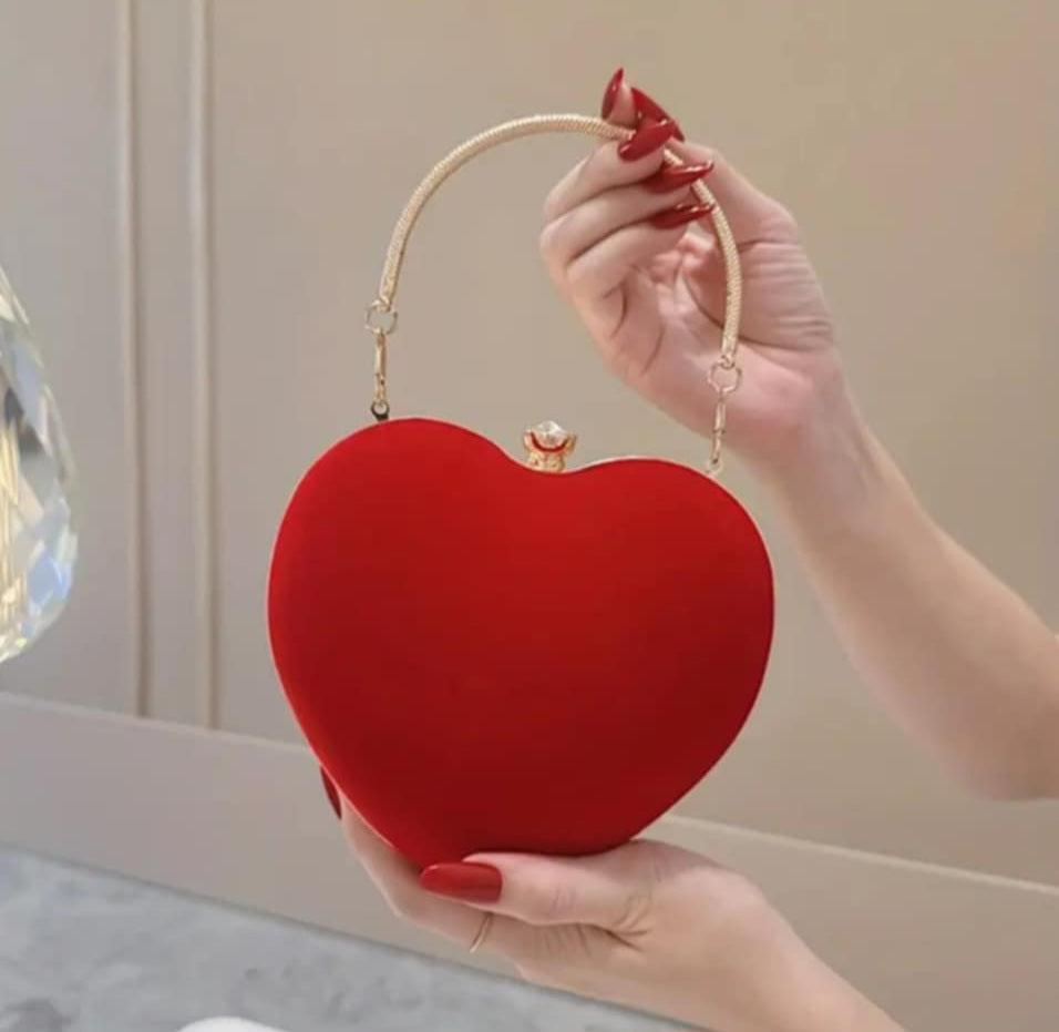 Heart-shaped handbag held in hand with chain handle